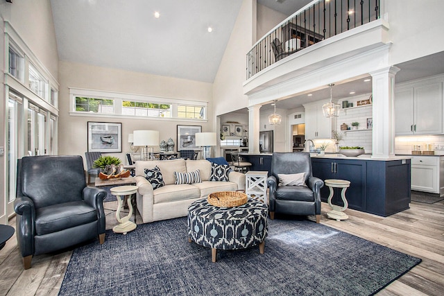 living room with a notable chandelier, light wood-type flooring, and high vaulted ceiling