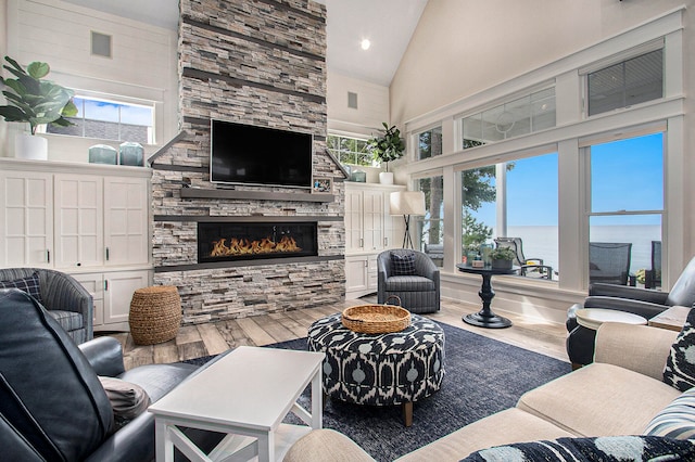 living room featuring a healthy amount of sunlight, a fireplace, hardwood / wood-style floors, and high vaulted ceiling