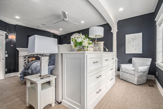 interior space with decorative columns, light carpet, and ceiling fan