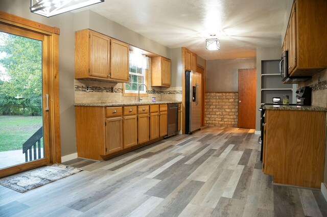 kitchen featuring tasteful backsplash, appliances with stainless steel finishes, light hardwood / wood-style flooring, and sink