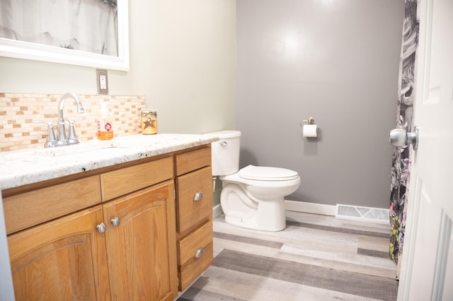 bathroom with backsplash, hardwood / wood-style flooring, vanity, and toilet