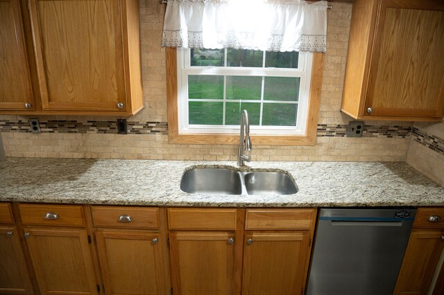 kitchen featuring light stone countertops, decorative backsplash, sink, and dishwasher