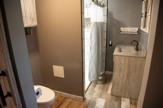 bathroom featuring curtained shower, wood-type flooring, vanity, and toilet