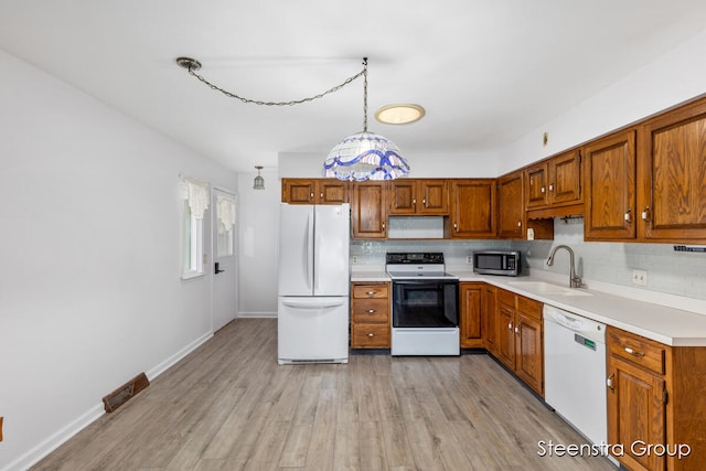 kitchen with white appliances, sink, light hardwood / wood-style floors, and tasteful backsplash