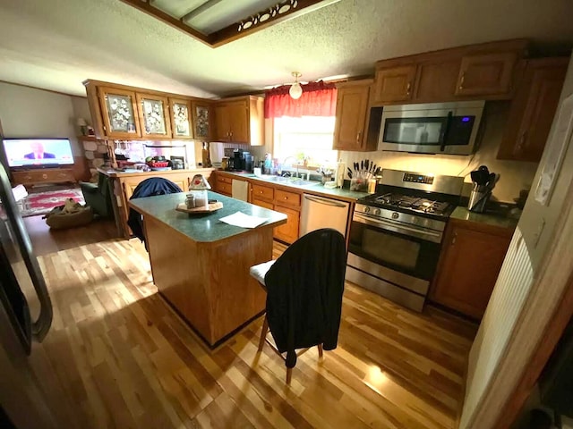 kitchen featuring a textured ceiling, appliances with stainless steel finishes, light hardwood / wood-style floors, and a kitchen island