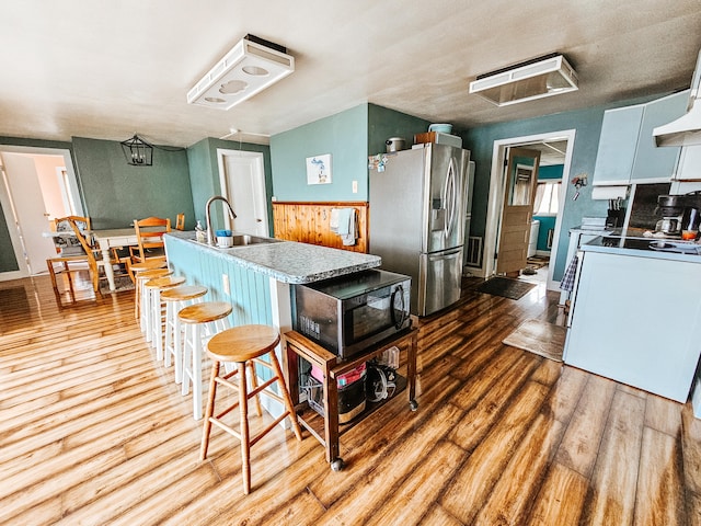 kitchen with stainless steel fridge, sink, light hardwood / wood-style floors, white cabinetry, and white range