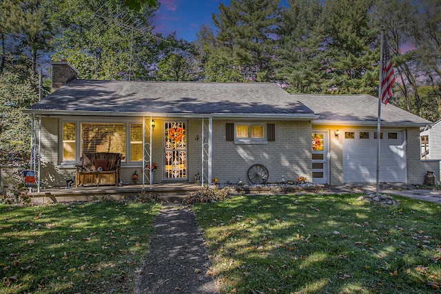 ranch-style house featuring a garage, a lawn, and covered porch