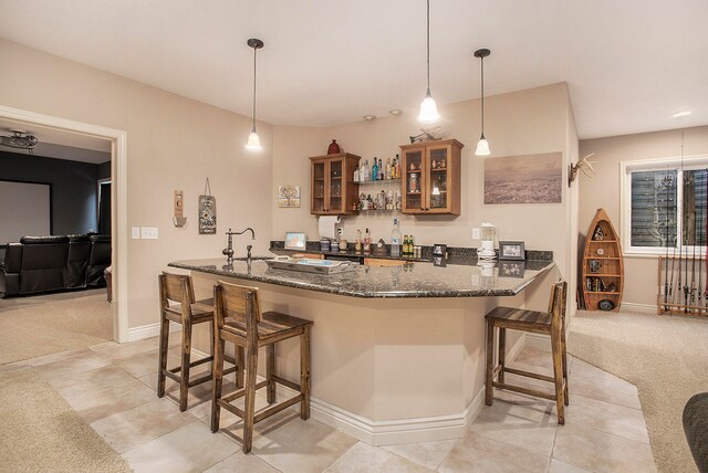 kitchen featuring dark stone countertops, pendant lighting, kitchen peninsula, and a breakfast bar