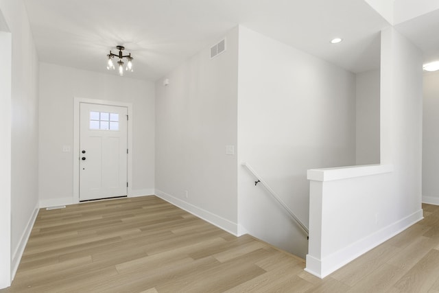 foyer entrance with a notable chandelier and light hardwood / wood-style flooring