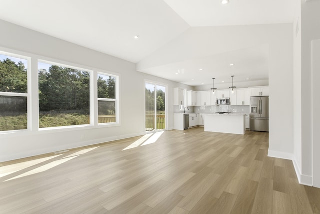 unfurnished living room with lofted ceiling, sink, and light hardwood / wood-style flooring