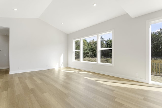 empty room featuring light hardwood / wood-style floors, vaulted ceiling, and a wealth of natural light