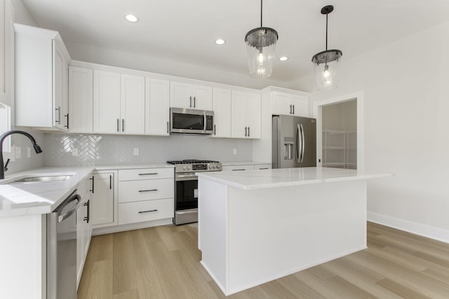 kitchen with decorative light fixtures, stainless steel appliances, white cabinetry, and a center island