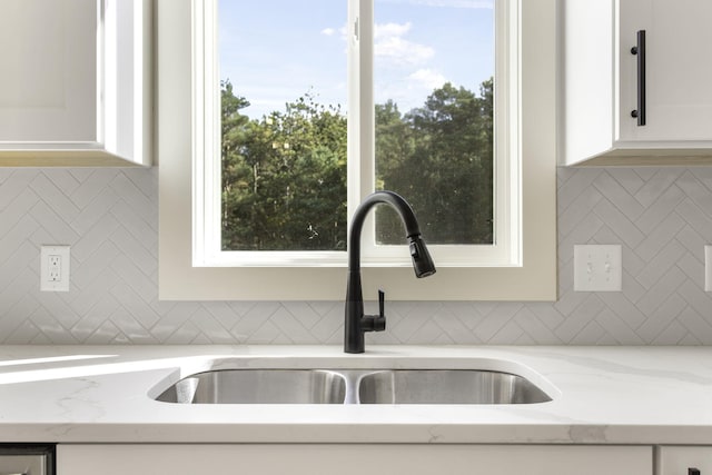 interior details with light stone countertops, sink, and white cabinets