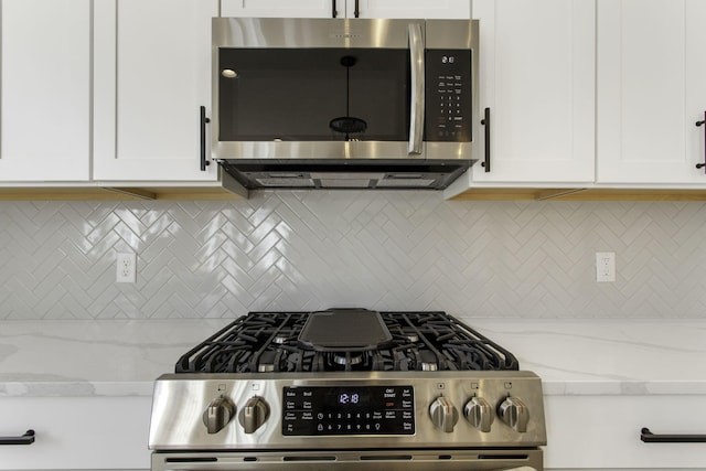 kitchen with light stone counters, backsplash, stainless steel appliances, and white cabinets