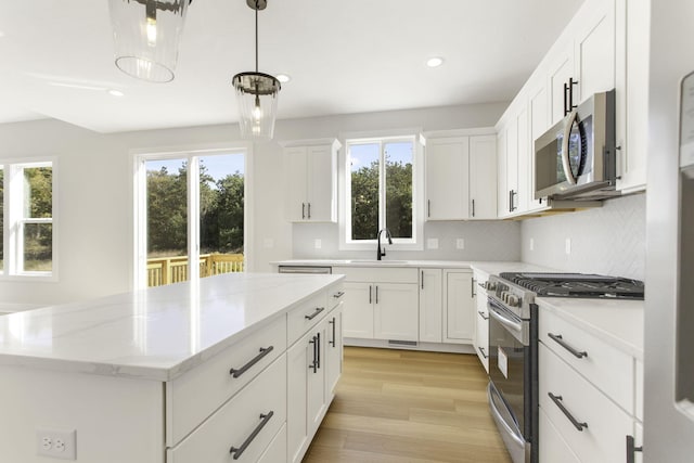 kitchen with a kitchen island, stainless steel appliances, plenty of natural light, and white cabinetry