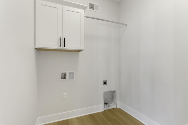 washroom featuring cabinets, hookup for a washing machine, light hardwood / wood-style flooring, and electric dryer hookup