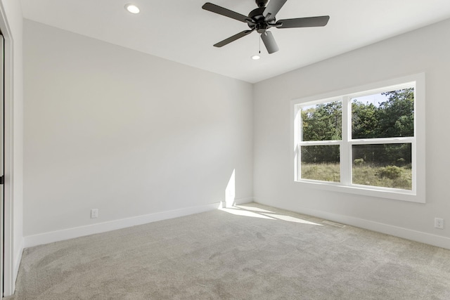 spare room with ceiling fan and light colored carpet