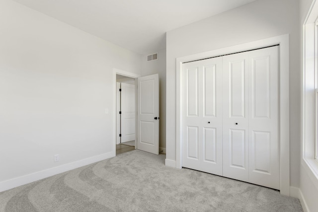 unfurnished bedroom with light carpet and a closet