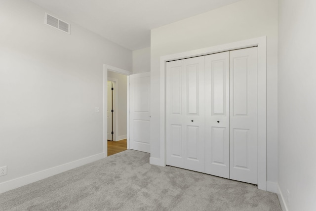 unfurnished bedroom with a closet and light colored carpet