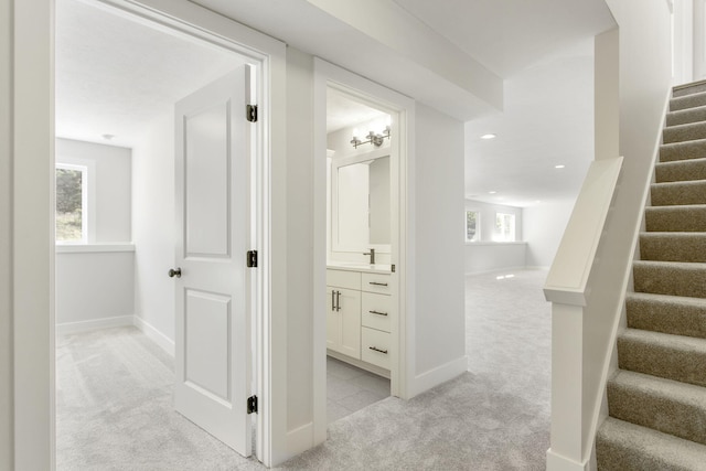 corridor with plenty of natural light, sink, and light carpet