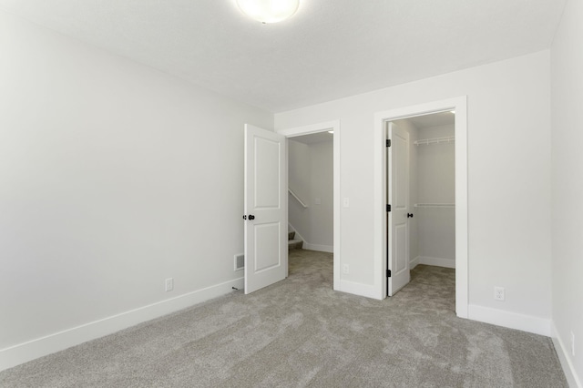 unfurnished bedroom with light colored carpet, a closet, and a walk in closet