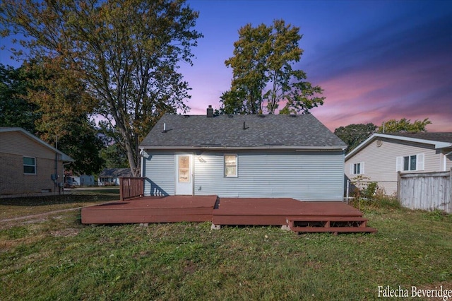 back house at dusk featuring a yard and a deck