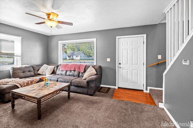 carpeted living room featuring ceiling fan and a textured ceiling