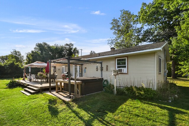 back of property featuring a yard, a deck, a pergola, and a hot tub