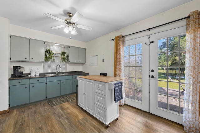 kitchen featuring a kitchen island, ceiling fan, wooden counters, sink, and dark hardwood / wood-style flooring