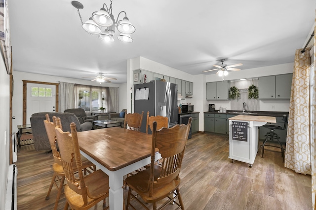 dining area featuring ceiling fan with notable chandelier, hardwood / wood-style floors, and sink