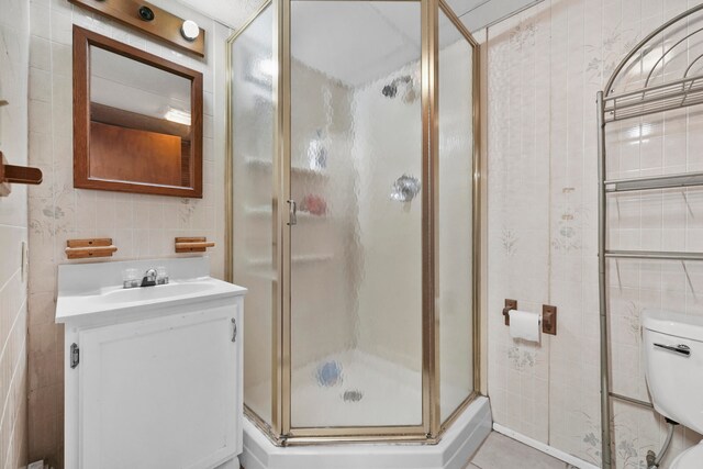 bathroom featuring vanity, tile walls, toilet, and an enclosed shower