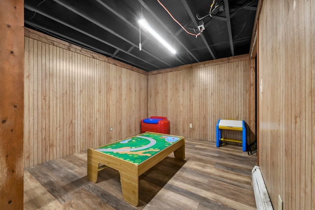 playroom with baseboard heating, wood walls, and hardwood / wood-style floors