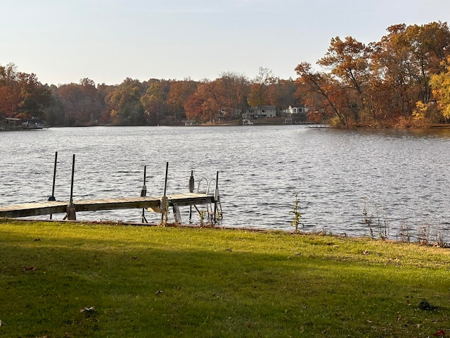 view of dock with a water view and a lawn