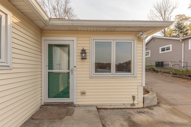 view of exterior entry featuring a patio and central AC unit