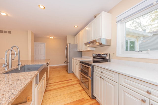 kitchen featuring white cabinetry, light stone countertops, sink, light hardwood / wood-style floors, and stainless steel appliances