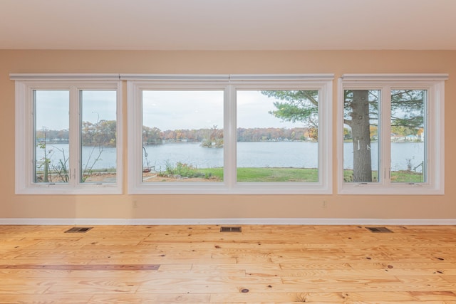 unfurnished room with a water view and light wood-type flooring