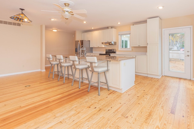 kitchen featuring a kitchen island with sink, white cabinets, stainless steel appliances, and light hardwood / wood-style floors