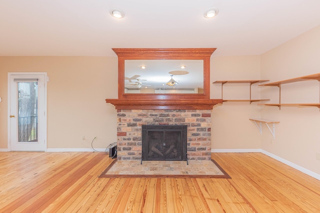 unfurnished living room featuring hardwood / wood-style flooring and a brick fireplace