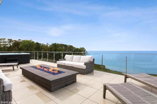 view of patio / terrace with an outdoor fire pit, a water view, and a hot tub