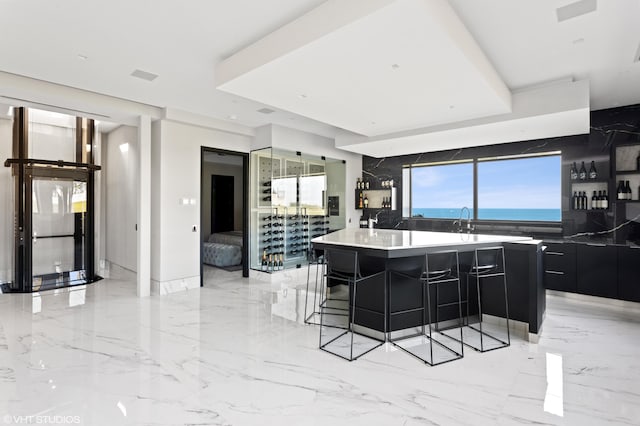 kitchen featuring a water view, a breakfast bar area, sink, and a spacious island