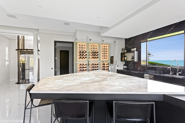 kitchen with sink, tasteful backsplash, a center island, a kitchen bar, and a water view