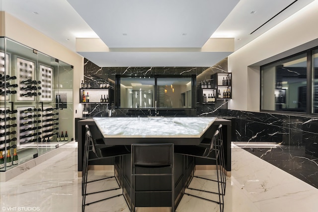 kitchen with sink, backsplash, a kitchen bar, and stone countertops