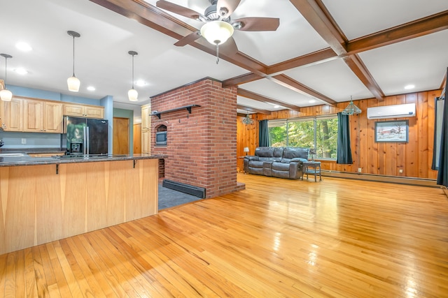 kitchen with hanging light fixtures, an AC wall unit, black fridge with ice dispenser, and light wood-type flooring