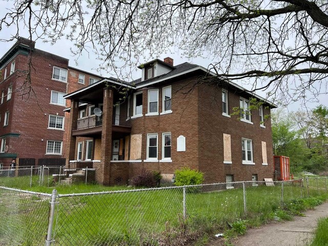 view of side of property with a balcony and a yard