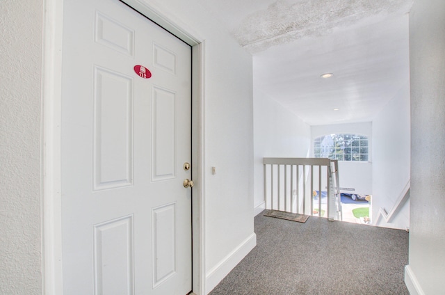 hallway with carpet flooring and a textured ceiling