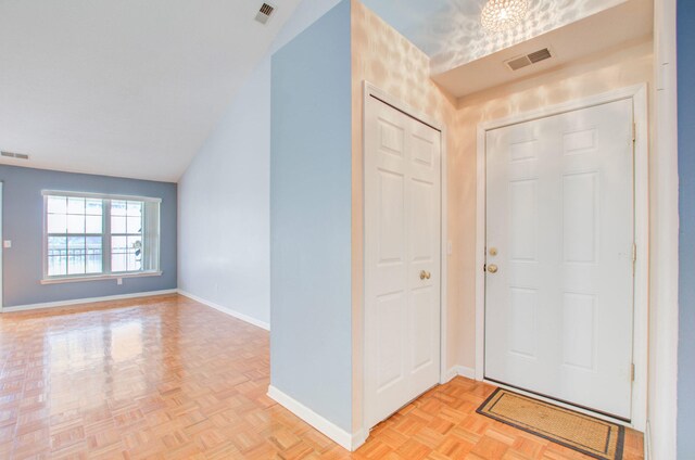 entrance foyer featuring light parquet floors and vaulted ceiling