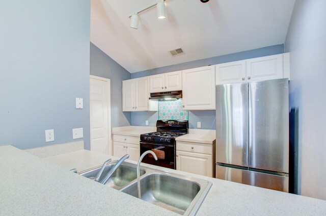 kitchen featuring lofted ceiling, white cabinets, stainless steel refrigerator, sink, and black gas stove