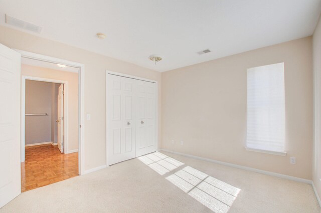 unfurnished bedroom with light parquet floors and a closet