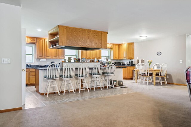 kitchen featuring kitchen peninsula, a breakfast bar area, and light carpet