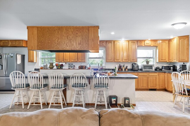 kitchen featuring appliances with stainless steel finishes, dark stone counters, and a wealth of natural light